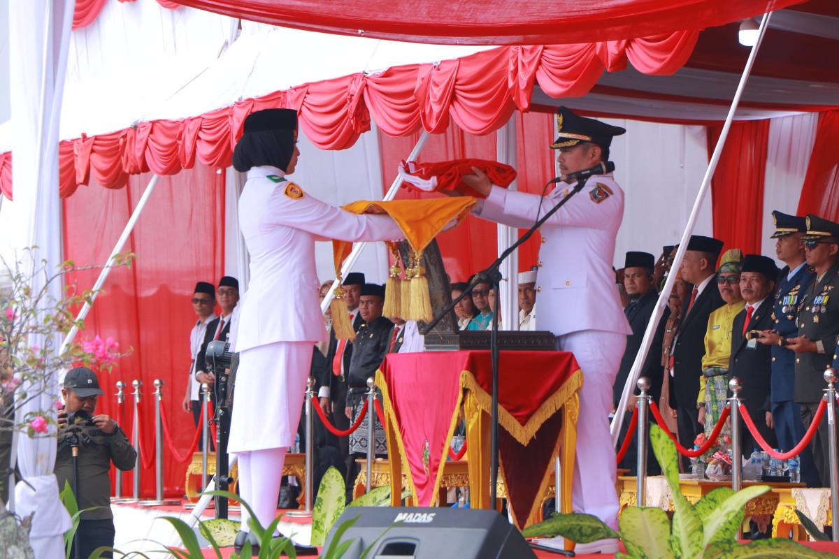 Pj Wali Kota Pekanbaru Risnandar Mahiwa Menyerahkan Duplikat Bendera Pusaka Merah Putih kepada Pengibar Bendera