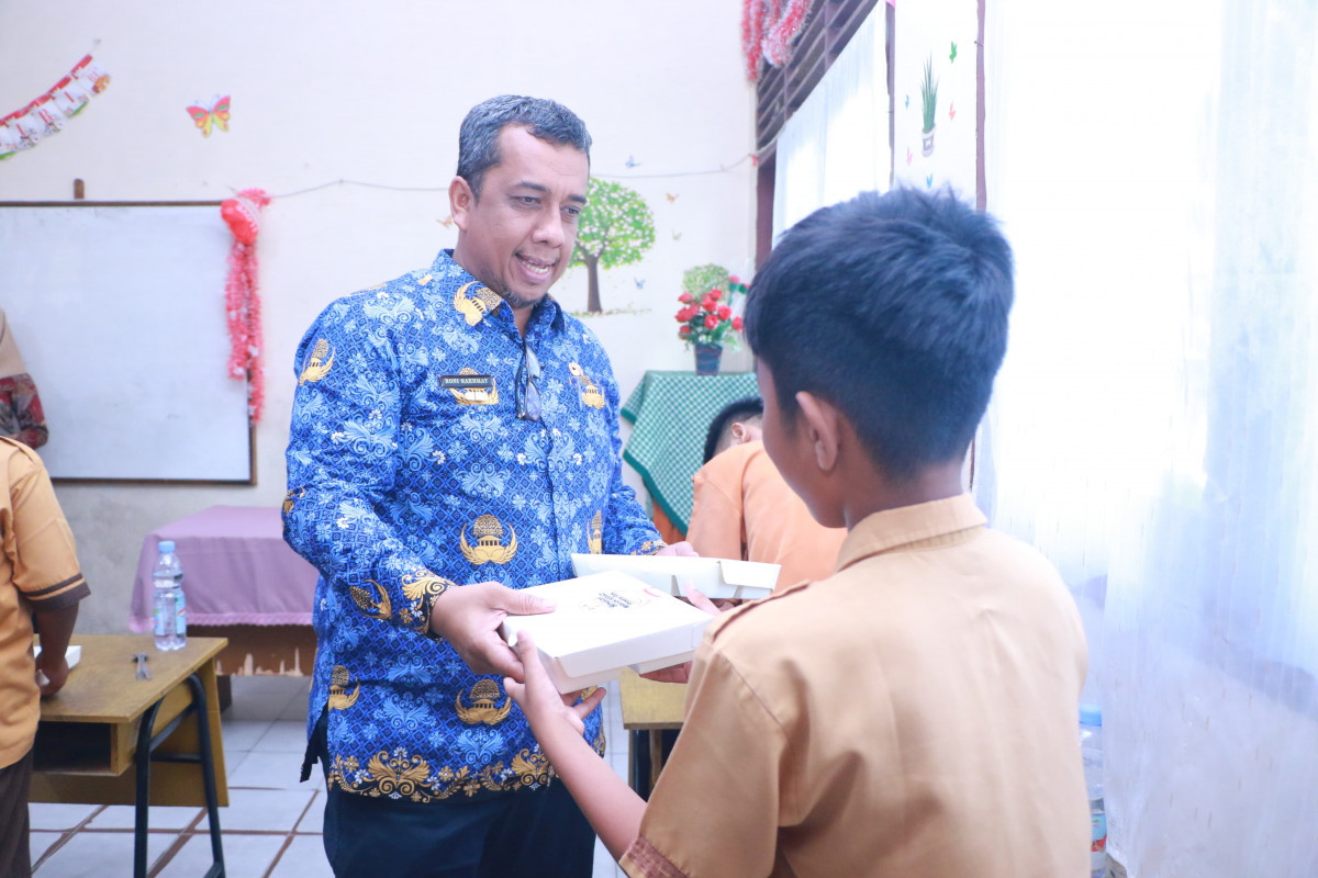 Pj Wali Kota Pekanbaru Roni Rakhmad Tampak Memberikan Paket Makan Siang Bergizi gratis kepada salah Seorang Murid