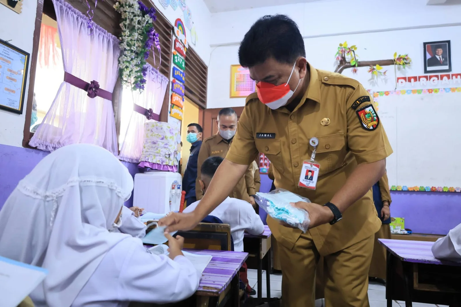 Plt Kepala Diadik Kota Pekanbaru Abdul Jamal  Membagikan masker kepada kepada peserta didik yang kembali mengikuti pembelajaran di sekolah.
